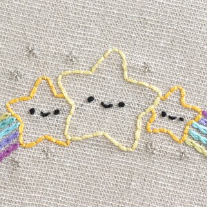May include: Three yellow embroidered stars with black eyes and mouths, with a rainbow of purple, blue, and green thread stitched behind them.