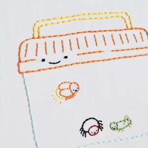 May include: A white embroidery hoop featuring a hand-stitched design of a glass jar with a smiling face. Inside the jar are three embroidered insects: a firefly, a spider, and a caterpillar.