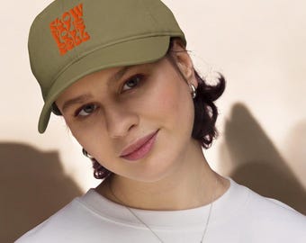 May include: A khaki green baseball cap with an orange embroidered design that says "Slow Love Rolls".