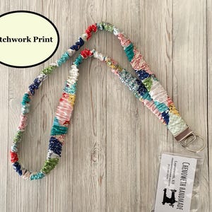 Puede incluir: Un cord&oacute;n con estampado de patchwork de colores con un cierre de metal y un llavero. El cord&oacute;n est&aacute; hecho de piezas de tela de varios colores, incluyendo rojo, azul, verde y rosa. El texto "Patchwork Print" est&aacute; en un &oacute;valo negro.