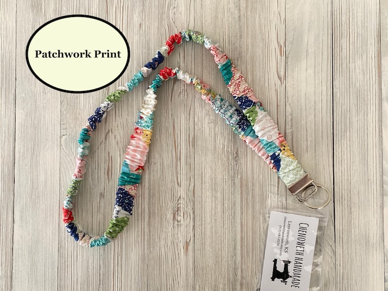 Puede incluir: Un cord&oacute;n con estampado de patchwork de colores con un cierre de metal y un llavero. El cord&oacute;n est&aacute; hecho de piezas de tela de varios colores, incluyendo rojo, azul, verde y rosa. El texto "Patchwork Print" est&aacute; en un &oacute;valo negro.