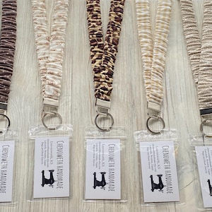 May include: A handmade wooden sign with the text "Welcome" in a playful font. The sign is painted white with a distressed finish, and features a decorative floral design in shades of pink and green. It measures approximately 12 inches wide.