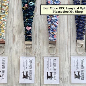 May include: Four fabric lanyards with key rings and clear ID holders. The lanyards feature floral and patterned designs in yellow, navy, and blue. Text on the ID holders reads "CHENOWETH HANDMADE" and contact information. Text at the top says "For More RPC Lanyard Options Please See My Shop".