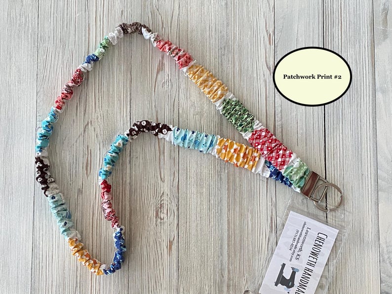 Puede incluir: Un cord&oacute;n de patchwork colorido con un cierre de metal y un llavero. La tela es una mezcla de patrones y colores, incluyendo rojo, azul, amarillo y verde. El texto "Patchwork Print #2" est&aacute; en un &oacute;valo color crema. El cord&oacute;n est&aacute; sobre un fondo de madera clara.