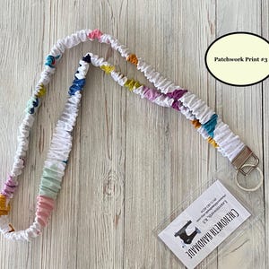 Puede incluir: Cord&oacute;n de tela blanco con estampado de patchwork en varios colores, incluyendo rosa, azul, amarillo y morado. El cord&oacute;n tiene un cierre met&aacute;lico y una etiqueta transparente con el texto "Chenoweth Handmade" y "Patchwork Print #3".