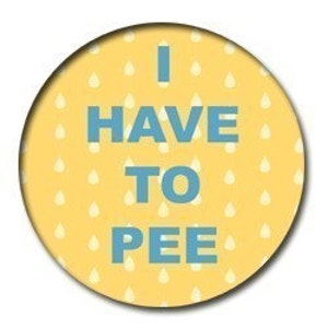 May include: A round, yellow button with a pattern of white teardrops. The text "I HAVE TO PEE" is printed in blue, centered on the button. The button has a slight shadow, suggesting a raised surface.