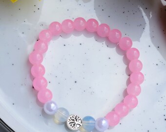 May include: Pink beaded bracelet with a silver tree charm and two white beads.