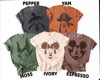 May include: Five short-sleeve crew neck t-shirts in pepper, yam, moss, ivory, and espresso colors. Each shirt features a dark graphic print of a Disney character: Goofy, Pluto, Daisy Duck, Minnie Mouse, and Mickey Mouse, with their names printed below.