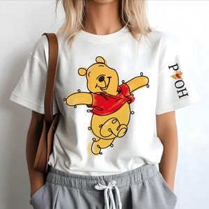 A person wearing a white t-shirt with a Winnie the Pooh character printed on it.
