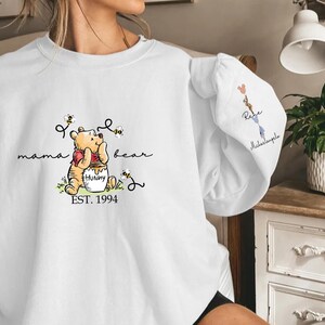 a woman holding a white shirt with a winnie the pooh on it