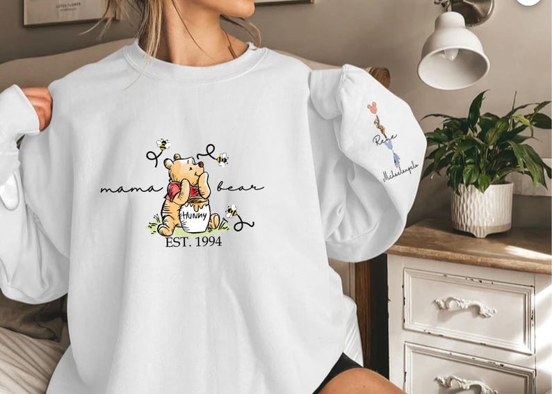 a woman holding a white shirt with a winnie the pooh on it