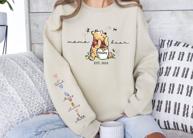 a woman sitting on a couch wearing a winnie the pooh sweatshirt