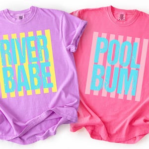 two t-shirts with different text and designs, one in purple and the other in pink.