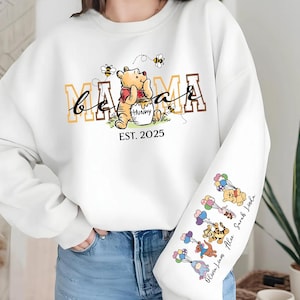 A person wearing a white sweatshirt with a Winnie the Pooh-themed design, including the character's name and the year 2015.