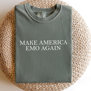 May include: A green t-shirt with the text "Make America Emo Again" printed in white.