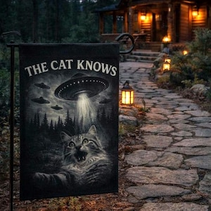 May include: Black garden flag featuring the text "THE CAT KNOWS" and a graphic of a cat looking up at a UFO. The UFO is beaming a light down on the cat. The background shows a forest and other UFOs.