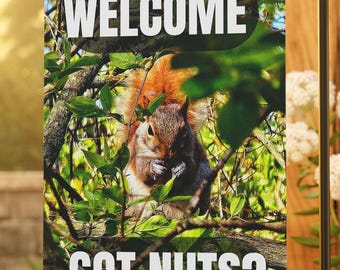 May include: A garden flag with a squirrel eating nuts in a tree. The flag says "Welcome Got Nuts?" in white text.