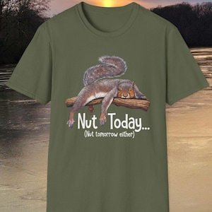May include: Khaki green t-shirt with a cartoon squirrel design. The squirrel is depicted resting on a branch, with a fluffy tail. The text "Nut Today... (Nut tomorrow either)" is printed below the squirrel in white.