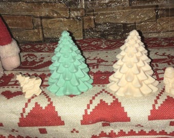 May include: A collection of Christmas-themed decorations. The image features a light green and a cream-colored Christmas tree, along with small, light-colored figurines. The items are arranged on a red and white patterned fabric.