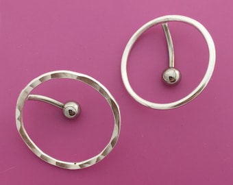 May include: Two silver hoop earrings with a small silver ball on the end of a curved bar that goes through the hoop.