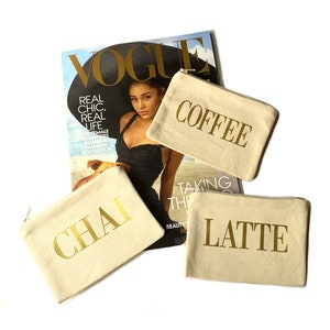 May include: Three beige canvas pouches with gold zipper pulls and gold lettering. The pouches are labeled "Chai", "Coffee", and "Latte".