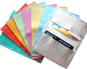 May include: A set of ten leather card holders in various colors, including turquoise, orange, yellow, pink, and light blue. The holders are arranged in a fan shape, with the silver holder on top. The silver holder has two cards inside, one with the text "Landis Card" and the other with the text "CARDHOLDER MAGAZINE".