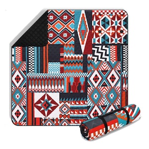 Könnte beinhalten: Eine farbenfrohe Picknickdecke mit geometrischem Muster in Rot-, Orange-, Türkis- und Schwarztönen. Die Decke ist rechteckig mit einem schwarzen, gesteppten Rand. Aufgerollt wird sie mit einem schwarzen Riemen befestigt. Das Design zeigt Diamanten, Zickzackmuster und andere Formen.