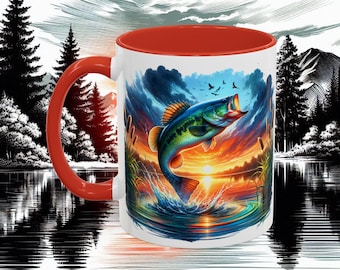 Puede incluir: Taza de cerámica blanca con interior y asa rojos. La taza presenta una vibrante ilustración de un róbalo saltando fuera del agua contra un fondo de puesta de sol. El diseño incluye una escena de lago con árboles y montañas.