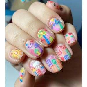 Könnte beinhalten: Eine Hand mit bemalten Nägeln mit bunten Cartoon-Designs. Die Designs umfassen Pilze, Herzen, eine Sonne, eine Wolke und Gebäude. Die Nägel sind mit einer transparenten Basis bemalt und die Designs sind in verschiedenen Farben umrandet.