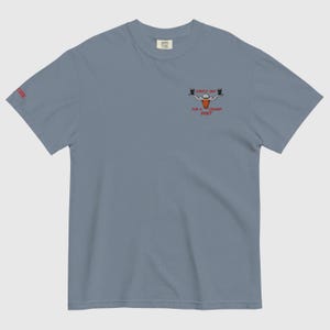 Puede incluir: Camiseta azul gris&aacute;ceo con un peque&ntilde;o gr&aacute;fico en la parte delantera que dice "Lovely Day for a Creamy Pint" en rojo. El gr&aacute;fico presenta dos vasos de cerveza y una cabeza de toro. La palabra "Cheer" est&aacute; impresa en la manga izquierda.