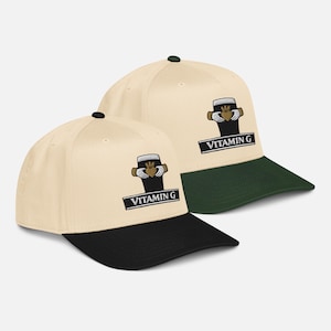 May include: Two baseball caps with a cream-colored crown and a black brim. Each cap features an embroidered logo of a beer glass with a heart and the text "VITAMIN G" in a black rectangle. One cap has a green brim.