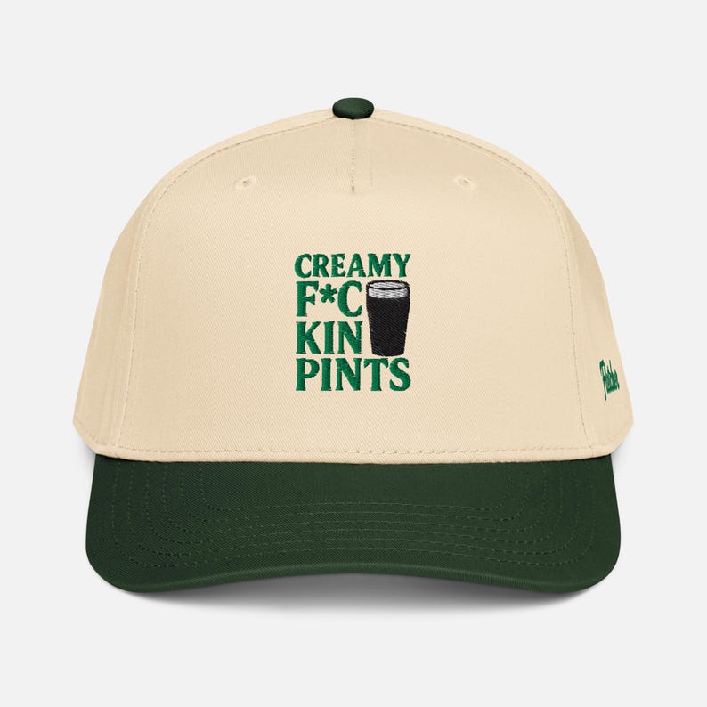 Puede incluir: Gorra de b&eacute;isbol crema y verde oscuro con el texto verde "CREAMY F*CKIN PINTS". La gorra tiene una visera verde oscuro y un peque&ntilde;o logotipo verde en el lateral.