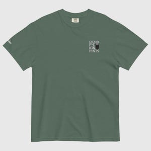 K&ouml;nnte beinhalten: Gr&uuml;nes T-Shirt mit dem Text "CREAMY F*CKIN PINTS" und einer Pintglas-Grafik. Das Shirt hat einen Rundhalsausschnitt und kurze &Auml;rmel. Der Text ist in einer serifenlosen Schriftart. Das T-Shirt ist locker geschnitten.