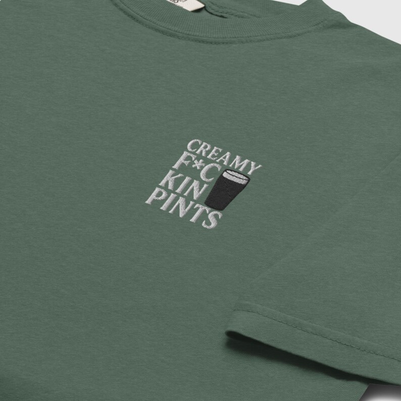 K&ouml;nnte beinhalten: Gr&uuml;nes T-Shirt mit der gestickten Aufschrift "CREAMY F*C KIN PINTS" und einer Abbildung eines Bierkrugs. Das Shirt hat einen Rundhalsausschnitt und ist aus weichem Stoff gefertigt.