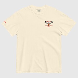 Puede incluir: Camiseta de color crema con un peque&ntilde;o gr&aacute;fico de una cabeza de toro con dos jarras de cerveza y el texto "LOVELY DAY FOR A CREAMY PINT". La palabra "CHER" est&aacute; impresa en la manga izquierda.