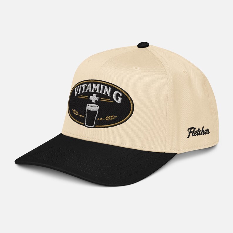 Puede incluir: Gorra de b&eacute;isbol color crema con visera negra. La gorra presenta un parche ovalado bordado con las palabras "Vitamin G" y un vaso de cerveza. El nombre "Fletcher" est&aacute; bordado en el lateral.