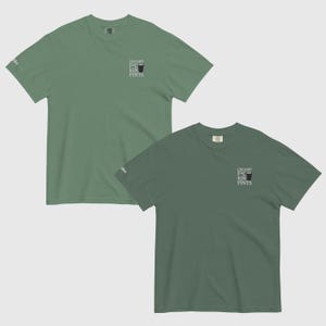 K&ouml;nnte beinhalten: Zwei kurz&auml;rmelige T-Shirts in Gr&uuml;nt&ouml;nen. Jedes Shirt hat den Text "CREAMY F*CKIN PINTS" und eine Grafik eines Pintglases auf der Vorderseite. Die Shirts werden vor einem hellgrauen Hintergrund gezeigt.