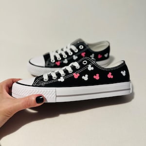 May include: Black canvas sneakers with white and pink Mickey Mouse silhouettes printed all over.