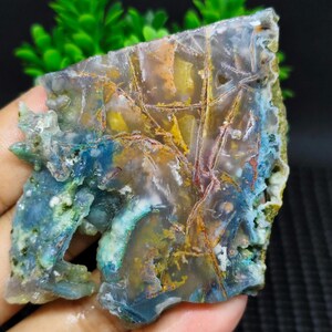 May include: A slice of agate with a variety of colors, including blue, green, yellow, and red. The agate has a natural, organic pattern and is translucent.