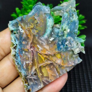 May include: A colorful agate slab with blue, green, yellow, and red hues. The agate has a layered, banded pattern and a smooth, polished surface.