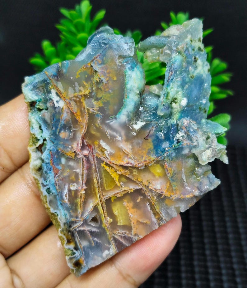 May include: A colorful agate slab with blue, green, yellow, and red hues. The agate has a layered, banded pattern and a smooth, polished surface.