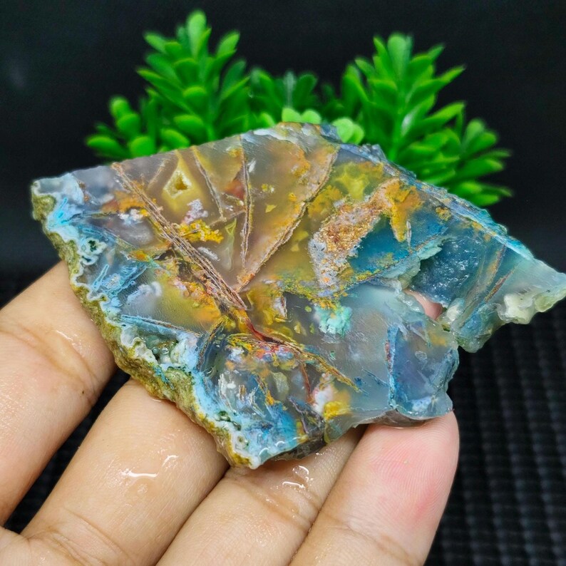 May include: A colorful agate slab with shades of blue, green, yellow, and orange. The agate has a unique pattern of veins and swirls.