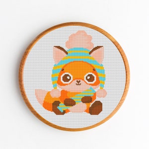 May include: A cross-stitch pattern of a cute orange fox wearing a blue and yellow striped hat with a pink pom-pom. The fox is sitting with its paws crossed and has big, round eyes.