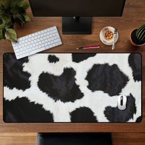 May include: Black and white cowhide patterned mouse pad with a black computer mouse on top of it.