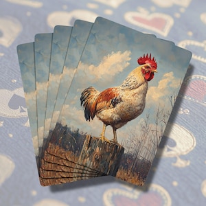 May include: A deck of playing cards featuring a detailed painting of a rooster perched on a wooden post. The rooster has red, brown, and white feathers against a backdrop of a cloudy sky. The cards are fanned out.