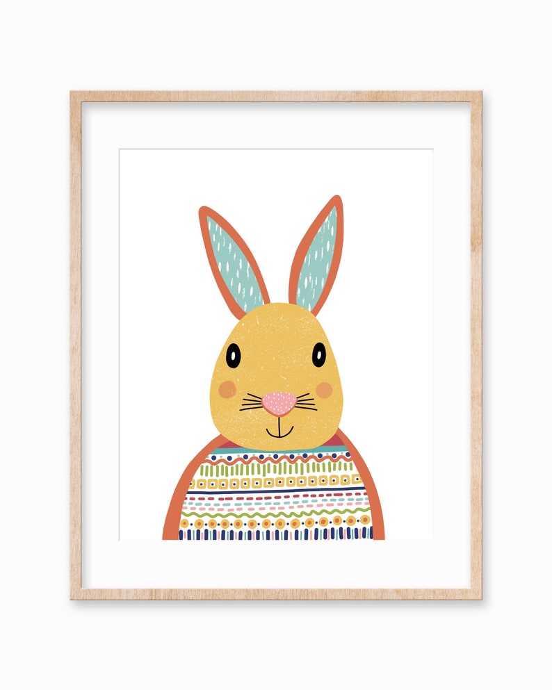 May include: A framed print featuring a cheerful, cartoon-style rabbit. The rabbit has a yellow face, orange ears with blue accents, and a patterned sweater in various colors. The artwork is set against a white background.