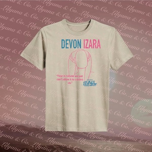 May include: Beige t-shirt with the name "DEVON IZARA" in blue and pink. A pink line drawing of a person is below the name, with the quote "Fear is natural we just can't allow it to control us." and the word "MAUL".