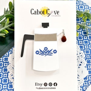 May include: White ceramic coffee pot with a blue floral design and a red glass drip. The pot is on a white card with the text "Cabot Cove creations" and "Etsy @cabotcovecreations".