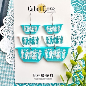 May include: Turquoise and white layered earrings in a retro bowl design. Each bowl features a white graphic of people and plants. The earrings are displayed on a white card with the text "Cabot Cove creations" and Etsy social media icons.