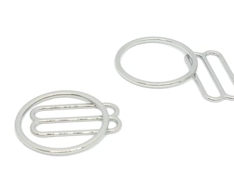 May include: Two silver metal bra strap adjusters. One adjuster has a round ring and the other has a round ring with a straight bar.